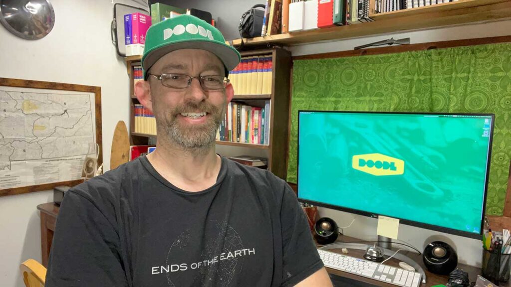 Graphic Designer Kevin Piazza of Doodl standing in front of his desk in Stevensville Montana