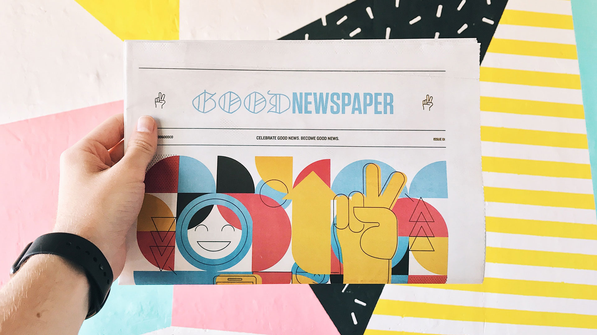 mans hand holding a graphic design newspaper blog post cover for Professional Designers Transcend Their Industry